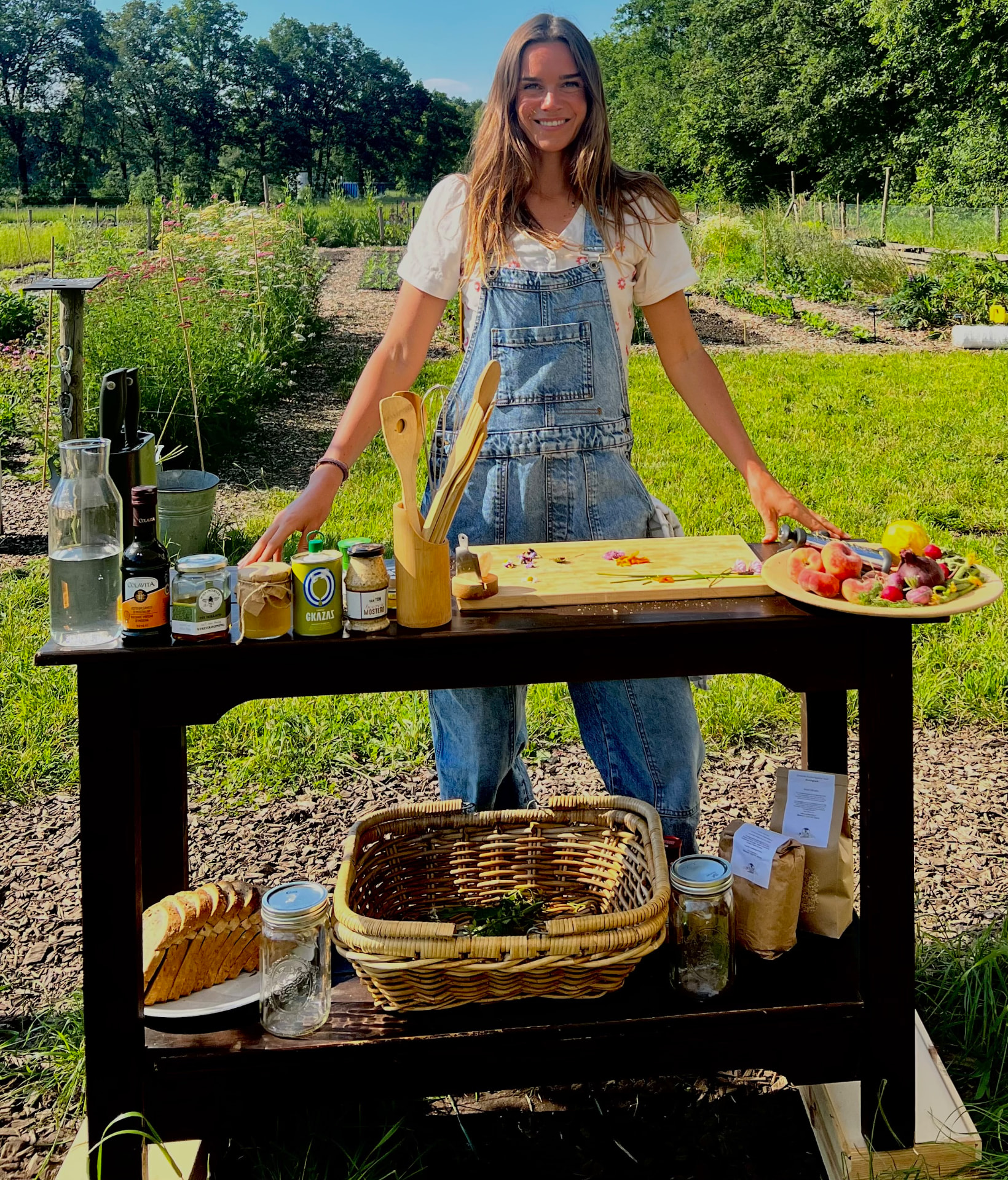 Claudia Maasdijk achter een tafel met lokale producten in een groene tuin